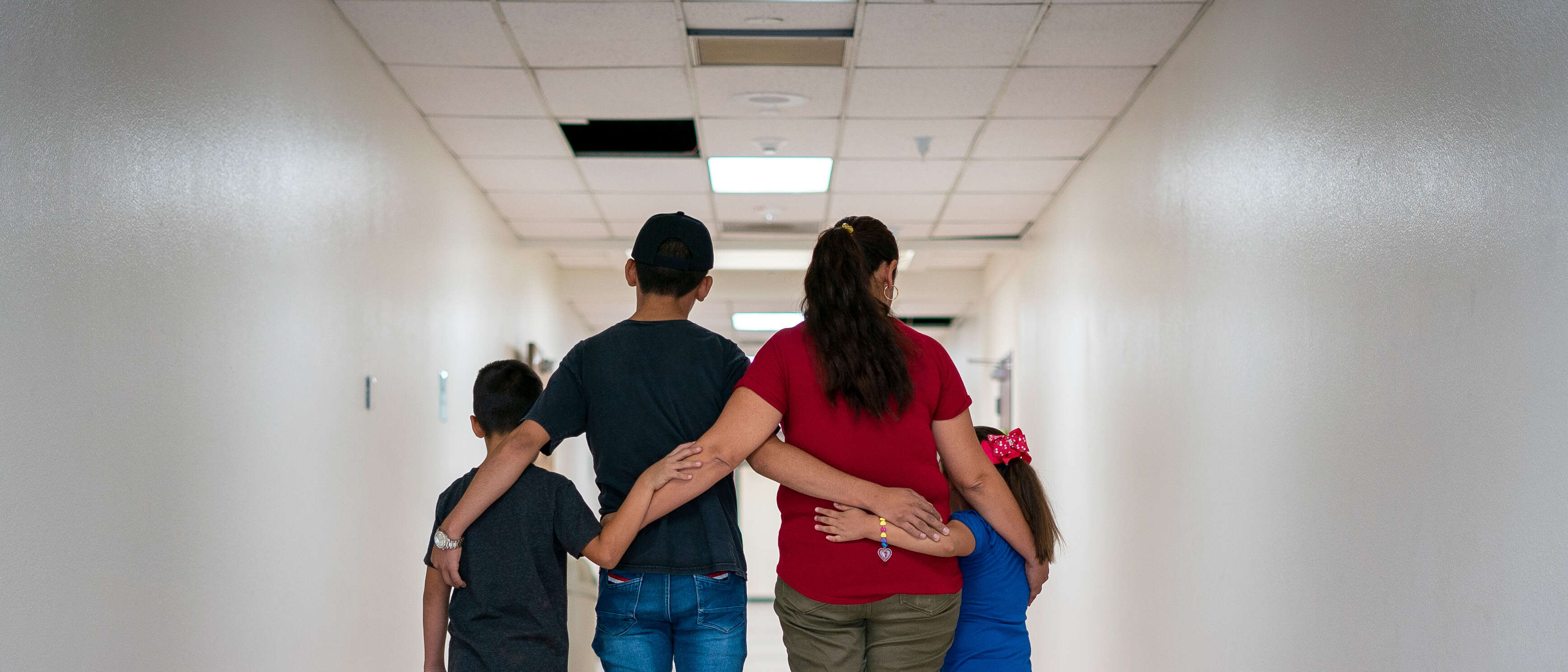 A family of four embrace each other with their backs turned to the camera.