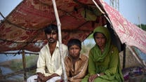 A family sits under a tent after flooding in Pakistan